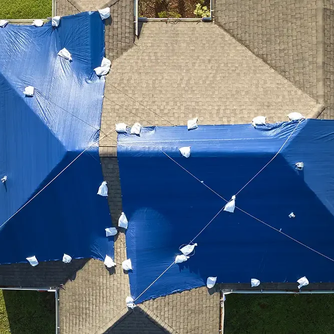 aerial-view-damaged-hurricane-ian-house-roof-covered-with-blue-protective-tarp-against-rain-water-leaking-until-replacement-asphalt-shingles